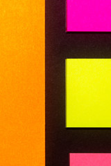 Yellow, orange and rose hue colorful office stickers on black paper. Office noteparer as reminder....