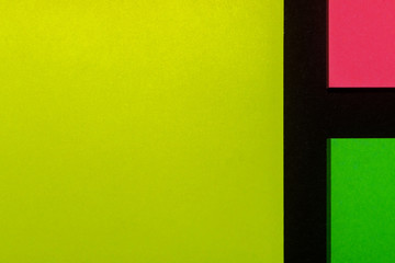 Green, yellow and pink hue colorful office stickers on black paper. Office noteparer as reminder. Isolated on black paper.