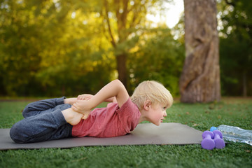 Little boy doing stretch during workout outdoors