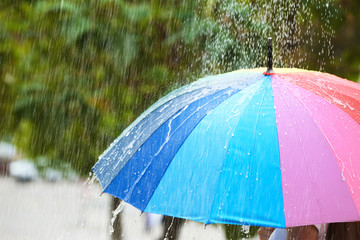 Person with bright umbrella under rain on street, closeup