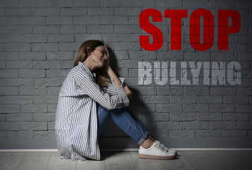 Lonely woman suffering from depression near brick wall