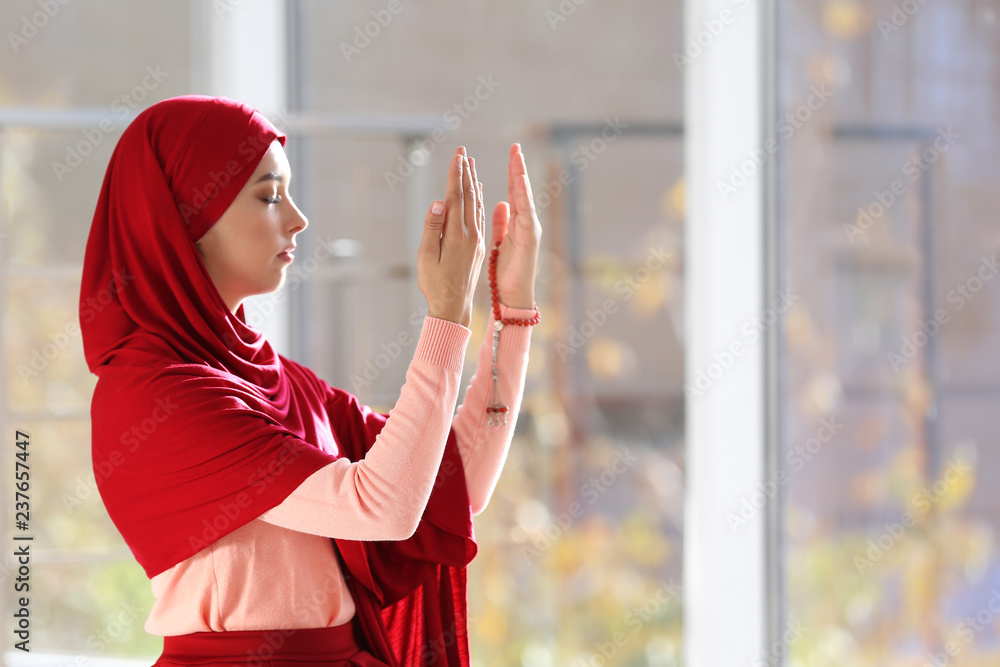 Canvas Prints Young Muslim woman in hijab praying indoors. Space for text