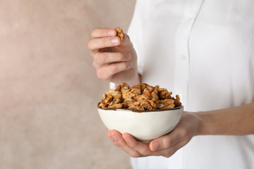 Woman holding bowl with tasty walnuts, closeup. Space for text