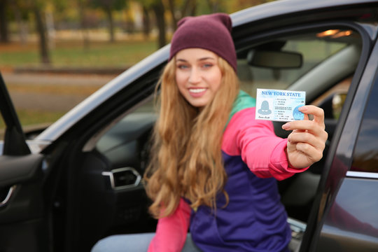 Happy woman holding driving license in car. Space for text