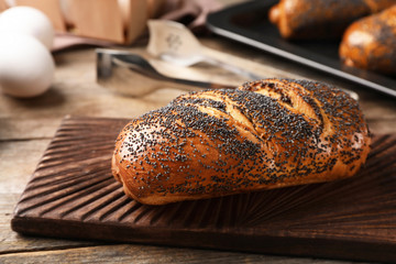 Board with freshly baked poppy seed roll on table