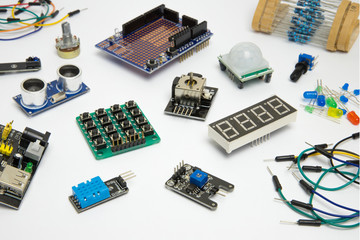 Various sensors and components for creating electrical circuits, devices or robots. Buttons, switches, motion sensor, digital display, wires, diodes, resistors on a white background.