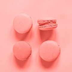 Sweet almond macaron or macaroon dessert cake colored in trendy color of year 2019 Living Coral background. Bright Macro color 16-1546. Minimal food bakery concept. Flat lay top view copy space