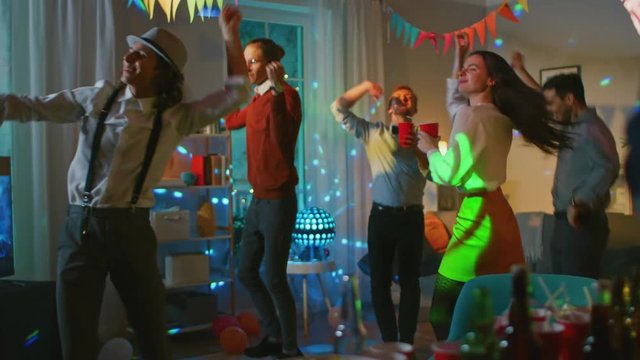 At the College House Costume Party: Diverse Group of Friends Have Fun, Dancing and Socializing and Drinking. Stylish Boys and Girls Dance in the Living Room. Disco Neon Lights Illuminating Room. 