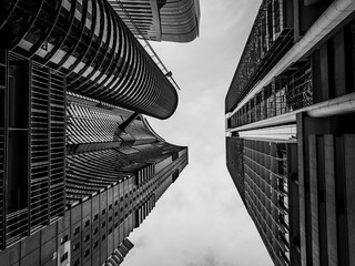 Looking up at tall metallic skyscrapers from below, black and white