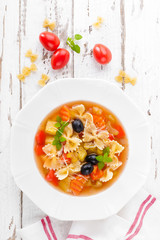 Minestrone, vegetarian soup with pasta and vegetables on white wooden rustic background. Traditional italian food. Top view