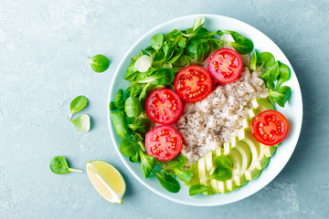 Oatmeal porridge with avocado and vegetable salad of fresh tomatoes and lettuce. Healthy dietary breakfast. Top view