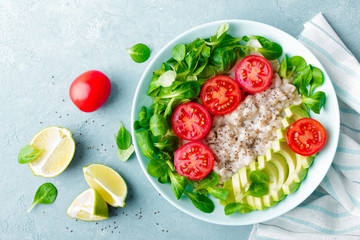 Oatmeal porridge with avocado and vegetable salad of fresh tomatoes and lettuce. Healthy dietary breakfast. Top view