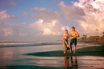 A man and a woman walk along a tropical beach with a guitar. Hawaii, ukulele