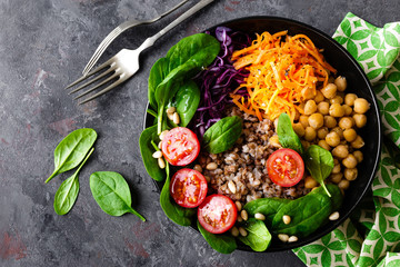 Healthy vegetarian dish with buckwheat and vegetable salad of chickpea, kale, carrot, fresh tomatoes, spinach leaves and pine nuts. Buddha bowl. Balanced food. Delicious detox diet.Top view