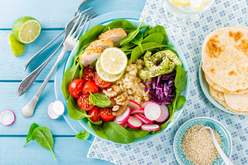 Bowl with grilled chicken meat, bulgur  and fresh vegetable salad of radish, tomatoes, avocado, kale and spinach leaves. Healthy and delicious summer lunch. Top view