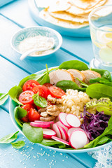 Bowl with grilled chicken meat, bulgur  and fresh vegetable salad of radish, tomatoes, avocado, kale and spinach leaves. Healthy and delicious summer lunch