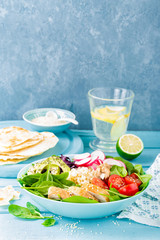 Bowl with grilled chicken meat, bulgur  and fresh vegetable salad of radish, tomatoes, avocado, kale and spinach leaves. Healthy and delicious summer lunch