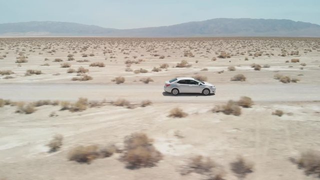 Aerial tracking Shot of a car driving through a desert on a dirt road