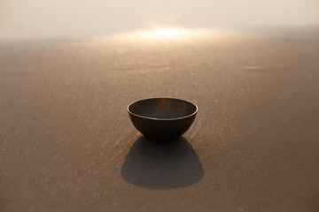 Tibetan singing bowl on the ocean on the sand. The background is blurred by sunlight. Place for...