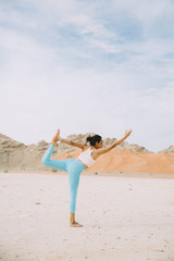 Young woman doing yoga in desert with mountains at sunrise time