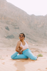 Young woman doing yoga in desert with mountains at sunrise time