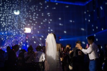 Happy bride dance at wedding party with guests and colour led lighting.