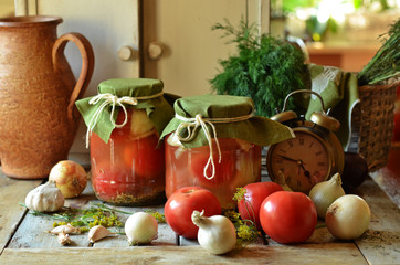 Pickled tomatoes in jars on a wooden background.