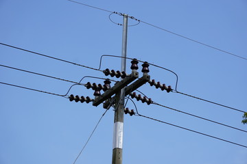 Electricity transmission line and electric pole on blue sky background.