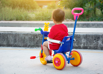 little girl wearing a red shirt She is sitting on her tricycle bicycle.