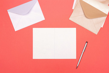 Top view of creative workspace with letter and envelopes on trendy coral background. Flat lay style. Place for text.
