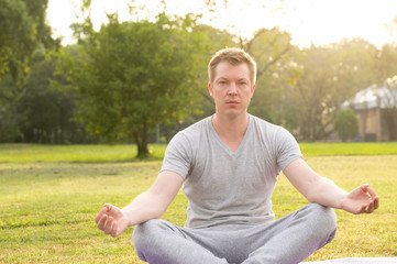 Fototapeta premium Young handsome man meditating at the park
