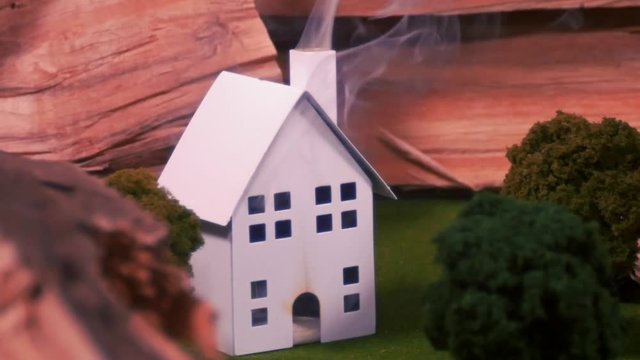 Fake little house is set on fire and smoking up.