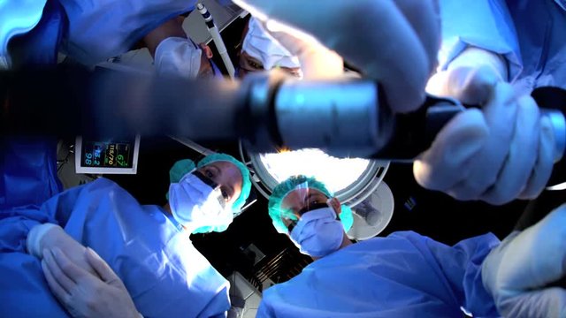 Patient POV Hospital Orthopedic Operation using mechanical instruments by Caucasian male and multi ethnic female specialist team in scrubs wearing protective clothing while operating on patient