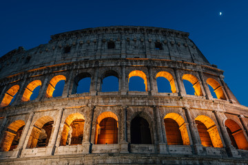 Fototapeta premium The Colosseum and moon at night in Rome, Italy.