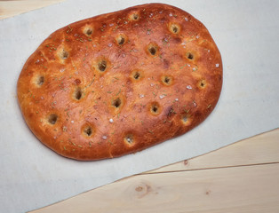 Traditional Italian focaccia homemade bread on lianna napkin. Wooden background. View from the top.