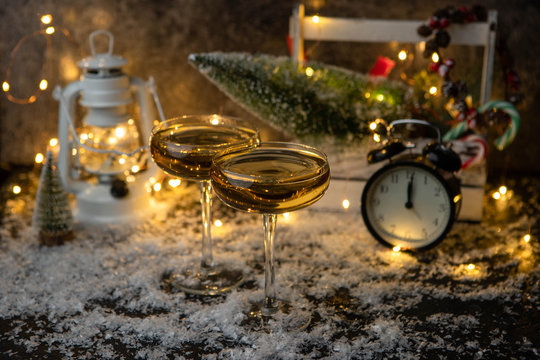 Image of two champagne glasses on blurred background with Christmas tree, lantern, clock