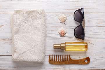 Fototapeta na wymiar Sea accessories on wooden background Suntan oil, comb, towel, seashells, sunglasses. Top view