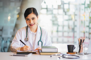 Female doctor working at office desk and smiling at camera