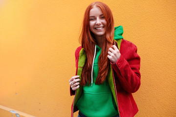 Emotive redhead girl grinning from happiness. Fashion girl in sportswear on yellow background.Young stylish hipster girl having fun and smiling near bright yellow urban wall.Spring lifestyle.