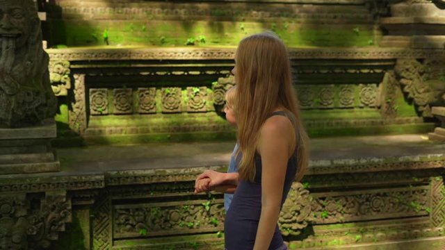 Slowmotion shot of a young woman and her little son visiting the Monkeys forest eco park in Ubud, Indonesia