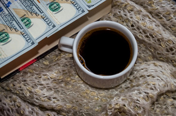 a cup of coffee and dollars on a book