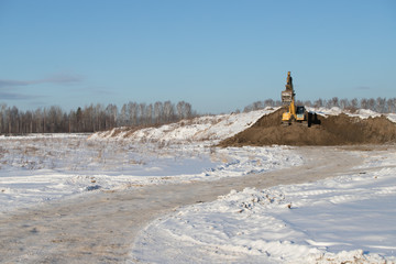 Yellow Excavator on a background of snowy mountains