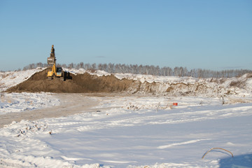 Yellow Excavator on a background of snowy mountains