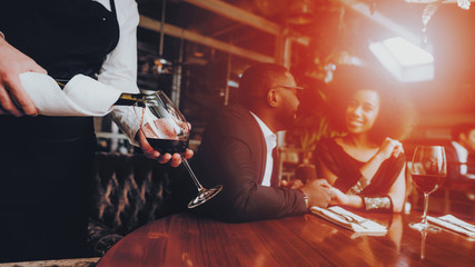 Waiter Pouring Wine to Glass Couple in Restaurant