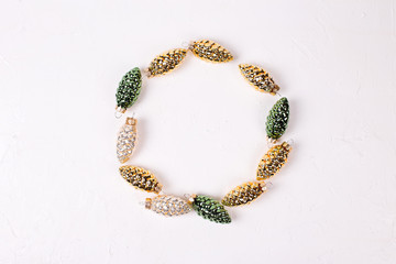 Rounde  frame from decorative golden, green and silver pine cones on white textured background.