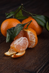 Slices of tangerines, tangerines with leaves on a wooden background