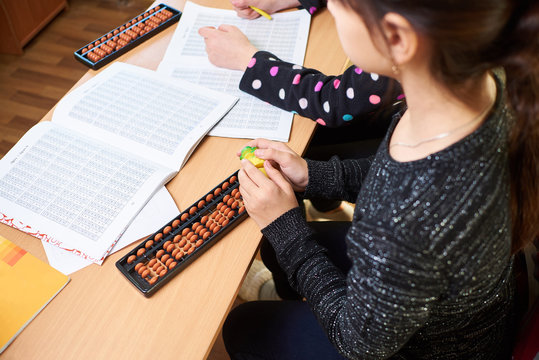the girl sits at the table and works on the accounts of mental arithmetic