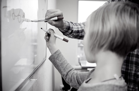 the girl with the teacher writes on the blackboard