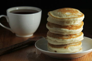 A stack of freshly backed pancakes and a cup of coffee