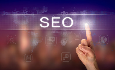 A hand selecting a SEO business concept on a clear screen with a colorful blurred background.